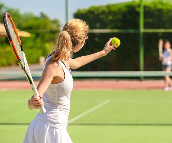 young woman getting ready to serve tennis ball